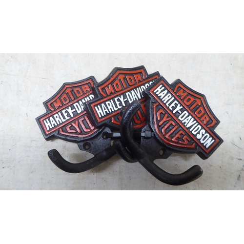 84 - A set of three cast iron, twin handled coat hooks, branded for 'Harley Davidson'  each 4