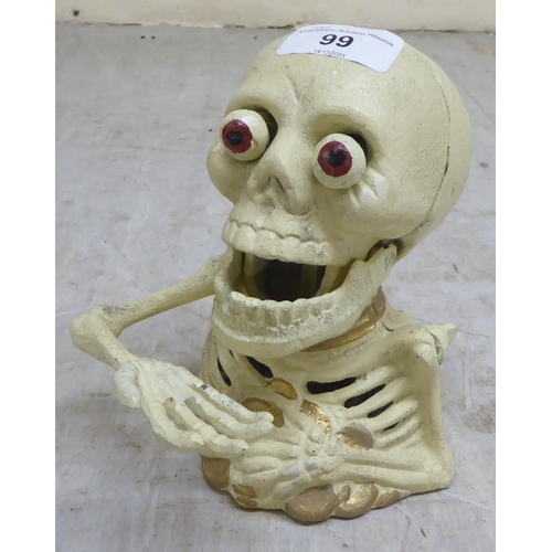 99 - A novelty white painted, cast iron money box, fashioned as a skeleton  6.5