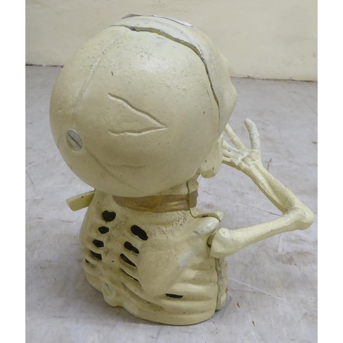 99 - A novelty white painted, cast iron money box, fashioned as a skeleton  6.5