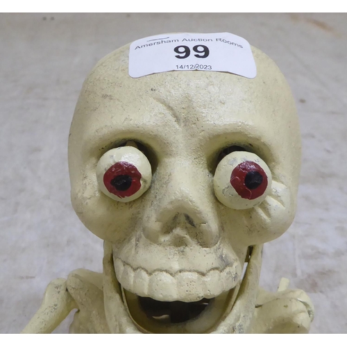 99 - A novelty white painted, cast iron money box, fashioned as a skeleton  6.5