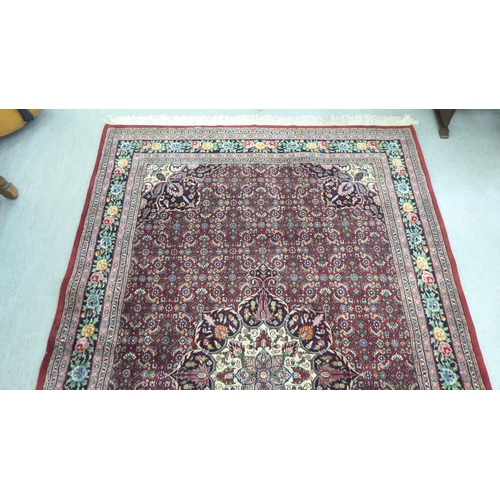 102 - An Indian rug, profusely decorated with repeating floral and other stylised designs, on a mainly red... 