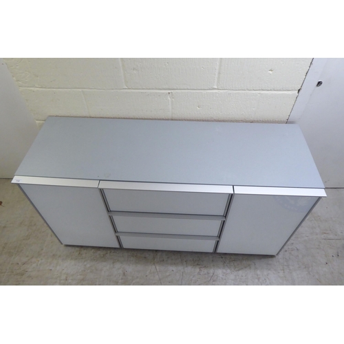 112 - A modern white and grey laminate and satin silver coloured metal mounted sideboard, comprising a ban... 