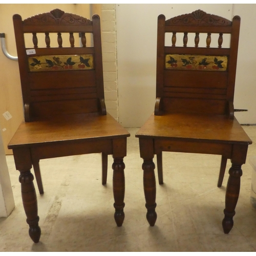 218 - A pair of Edwardian oak hall chairs, the solid seats raised on ring turned forelegs