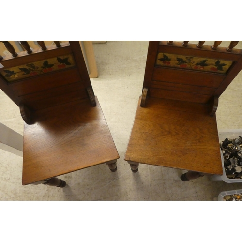 218 - A pair of Edwardian oak hall chairs, the solid seats raised on ring turned forelegs