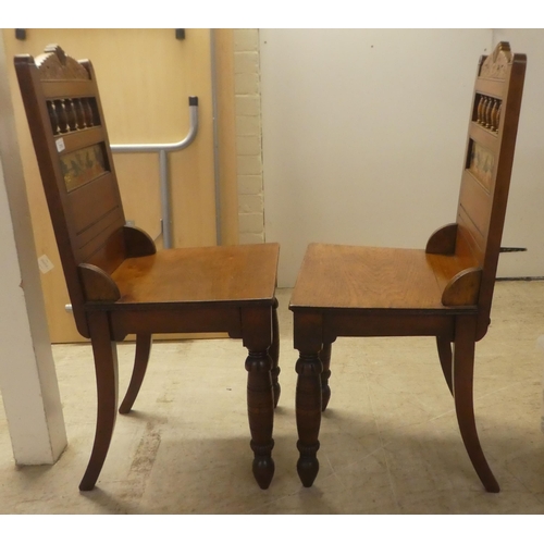 218 - A pair of Edwardian oak hall chairs, the solid seats raised on ring turned forelegs