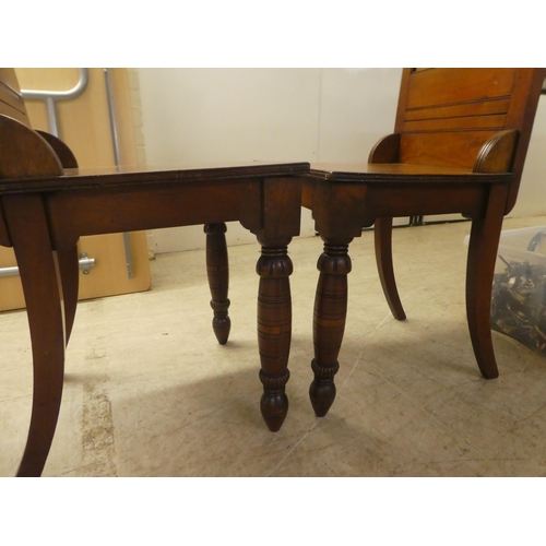 218 - A pair of Edwardian oak hall chairs, the solid seats raised on ring turned forelegs