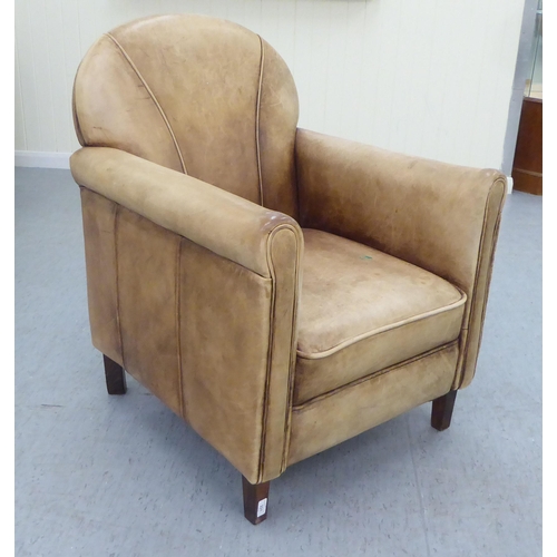 331 - An Art Deco inspired soft brown hide upholstered enclosed armchair, raised on tapered legs