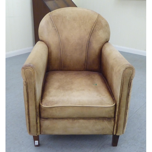 331 - An Art Deco inspired soft brown hide upholstered enclosed armchair, raised on tapered legs