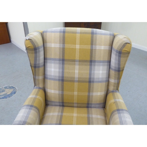 332 - A modern fabric upholstered, enclosed wingback armchair, raised on tapered forelegs