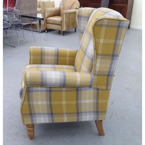 332 - A modern fabric upholstered, enclosed wingback armchair, raised on tapered forelegs