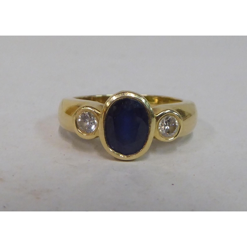 341 - A yellow metal ring, set with a blue stone, flanked by two diamonds