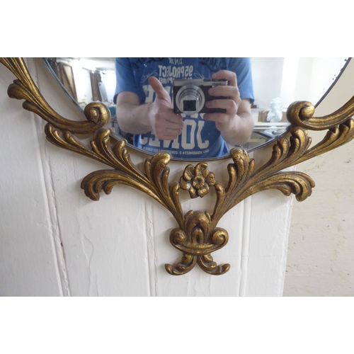 71 - A 20thC mirror, the shaped bevelled plate, set in a Georgian style cast metal mount  29