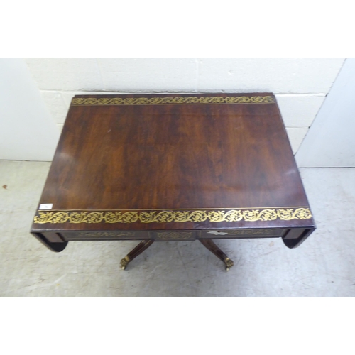 73 - A Regency brass inlaid rosewood sofa table with two frieze drawers, raised on a column and splayed q... 