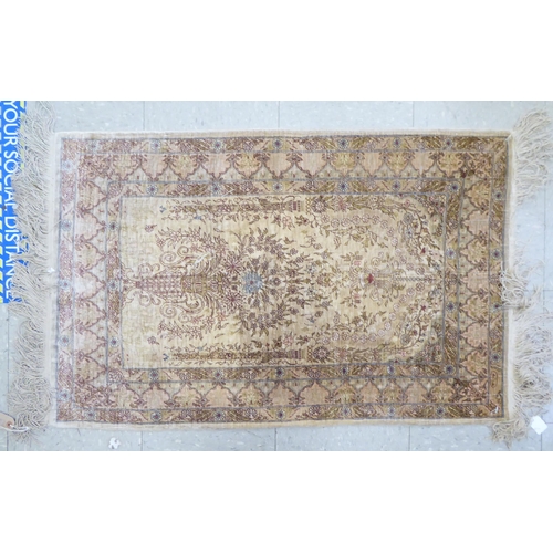 100 - A Hereke silk rug with floral motifs, on a beige ground  42