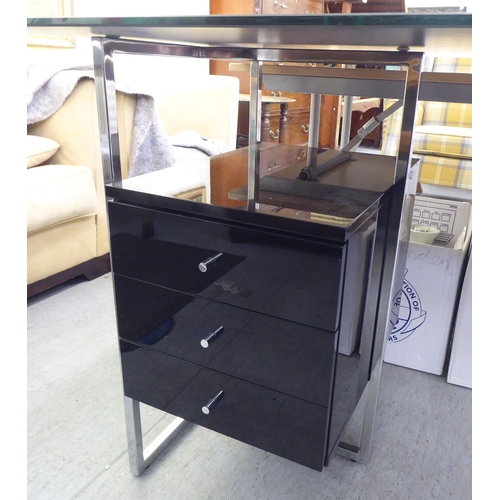 115 - A modern chrome framed, glass top desk with three drawers, raised on rectangular legs  30