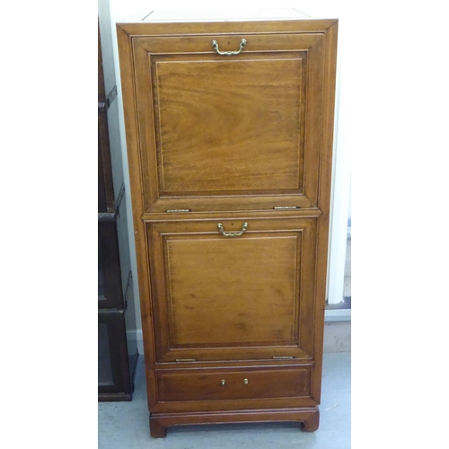 211 - A mid 20thC Chinese fruitwood music cabinet with two fall front doors, raised on bracket feet  44