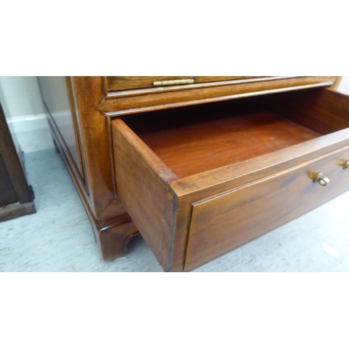 211 - A mid 20thC Chinese fruitwood music cabinet with two fall front doors, raised on bracket feet  44