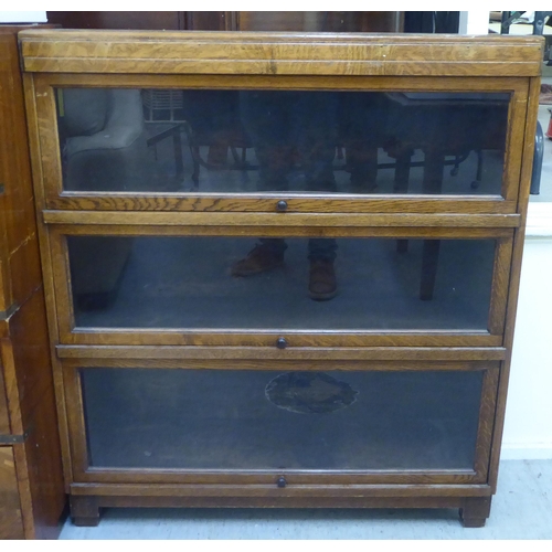 226 - A 1930s oak bookcase with three glazed lift & slide doors, raised on bracket feet  40