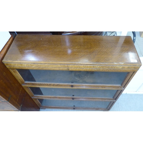 226 - A 1930s oak bookcase with three glazed lift & slide doors, raised on bracket feet  40