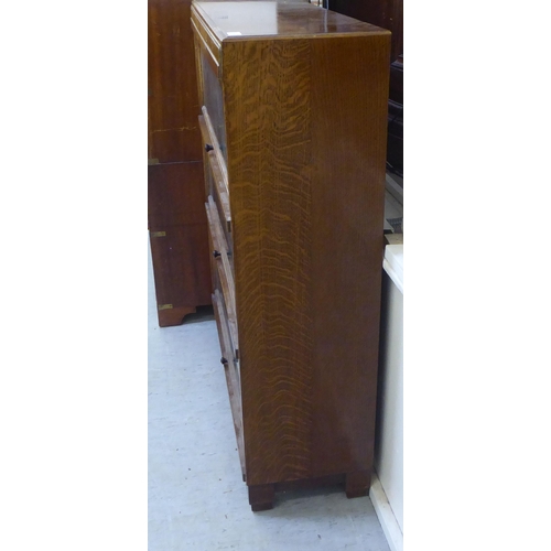 226 - A 1930s oak bookcase with three glazed lift & slide doors, raised on bracket feet  40