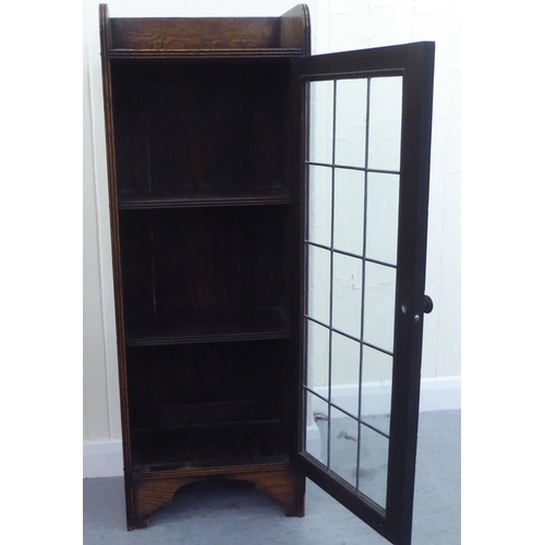 29 - A 1920s oak bookcase, the lead framed and glazed door revealing three shelves, raised on bracket fee... 