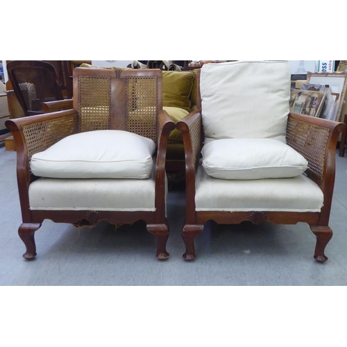 34 - A 1930s stained beech framed bergere suite, raised on cabriole legs  comprising a three person sette... 