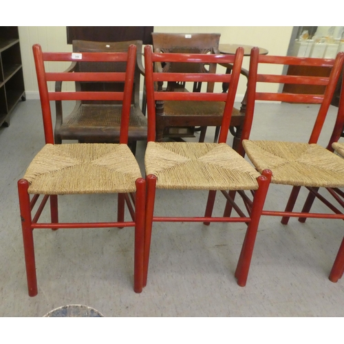 349 - A set of four red stained beech framed kitchen chairs, each with a rush seat, raised on turned legs