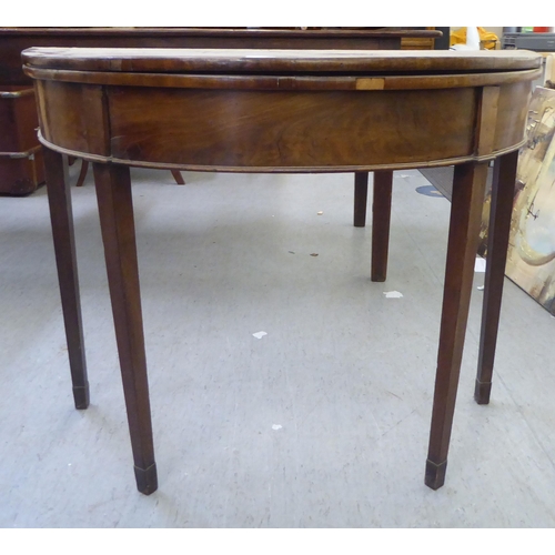 377 - A Regency mahogany demi-lune card table with a foldover top, raised on square, tapered legs  28... 