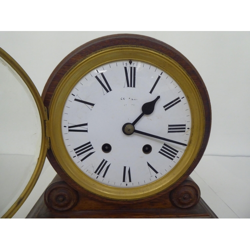 4 - An early 20thC oak mantel clock, faced by a Roman dial, on a plinth  11