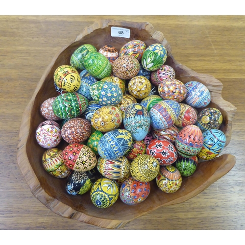 68 - Painted chickens' eggs, decorated in floral, geometric and other designs; and a rough carved wooden ... 