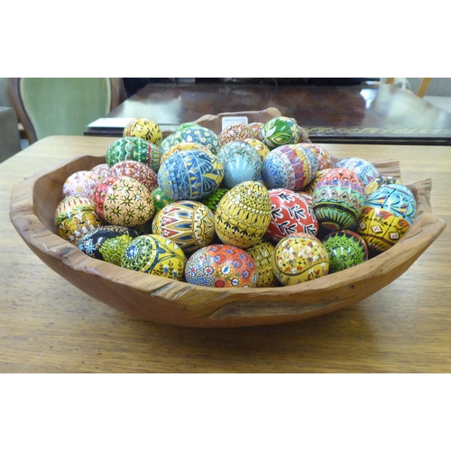 68 - Painted chickens' eggs, decorated in floral, geometric and other designs; and a rough carved wooden ... 