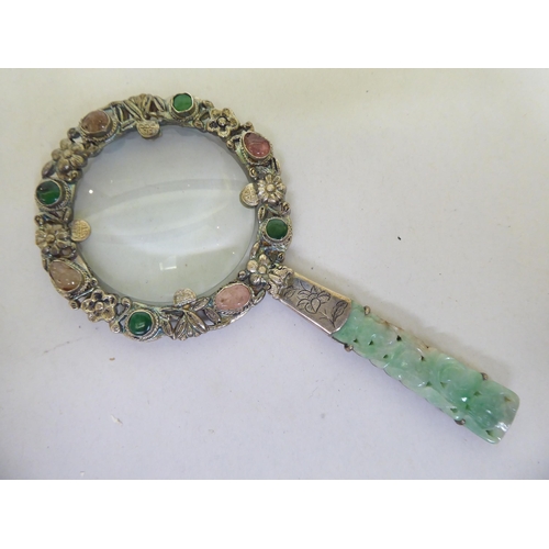 82 - A Chinese white metal magnifying glass set with jade and cabochon cut gems