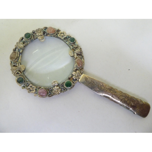 82 - A Chinese white metal magnifying glass set with jade and cabochon cut gems