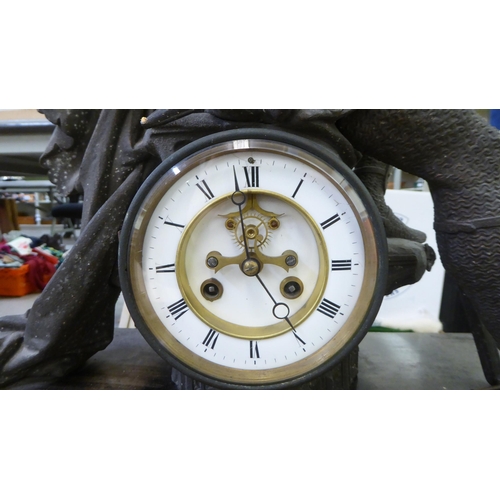 141 - A late 19thC mantel clock, surmounted by a seated, disconsolate Knight, on a plinth and attendant de... 