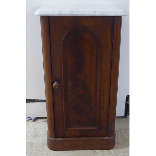 145 - A late Victorian mahogany pot cupboard with a mottled grey marble top, over a full height door, on a... 