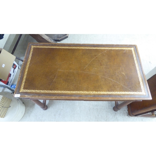 148 - A mid 20thC Continental style mahogany writing table with a tooled and gilded old gold coloured hide... 