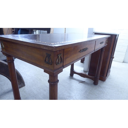 148 - A mid 20thC Continental style mahogany writing table with a tooled and gilded old gold coloured hide... 