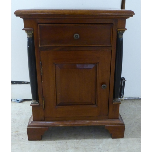 149 - A modern panelled mahogany cupboard with a box drawer, over a door, flanked by recessed pillars, rai... 