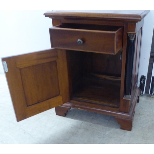 149 - A modern panelled mahogany cupboard with a box drawer, over a door, flanked by recessed pillars, rai... 