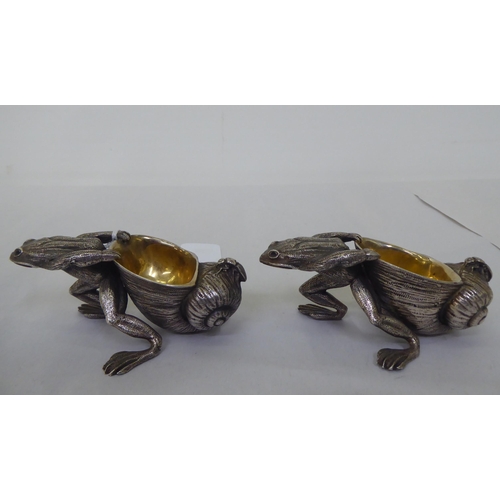 151 - A pair of parcel gilt and white metal novelty salt cellars, each fashioned as a frog, pulling a snai... 