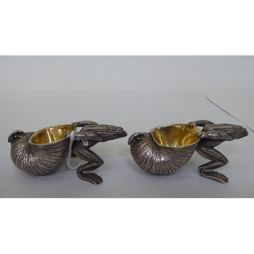 151 - A pair of parcel gilt and white metal novelty salt cellars, each fashioned as a frog, pulling a snai... 