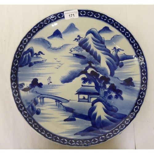 171 - A modern Oriental china footed charger, decorated in blue and white with ships in a landscape  ... 