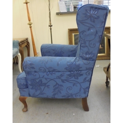 191 - A modern blue fabric upholstered wingback armchair, raised on cabriole legs