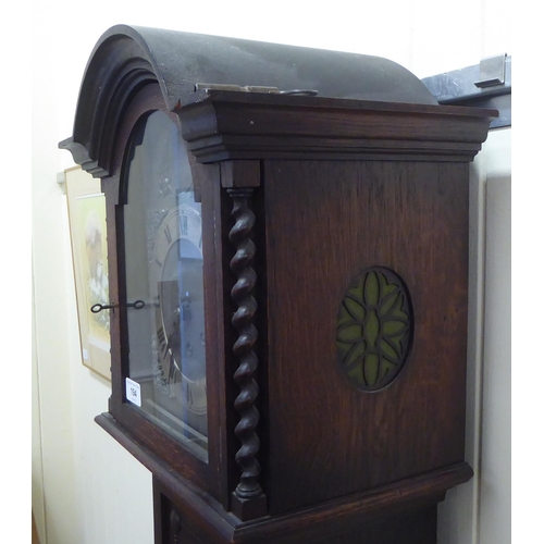 194 - An early 20thC oak cased granddaughter clock, the arched hood decorated with barleytwist columns, co... 