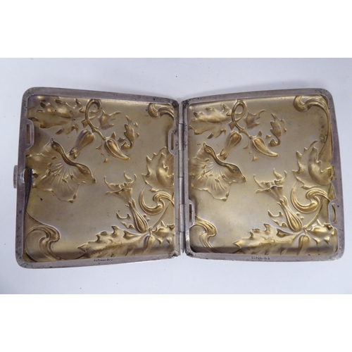 20 - An Art Nouveau silver coloured metal, folding cigarette case, on a button clasp, embossed and chased... 