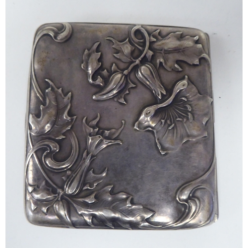 20 - An Art Nouveau silver coloured metal, folding cigarette case, on a button clasp, embossed and chased... 