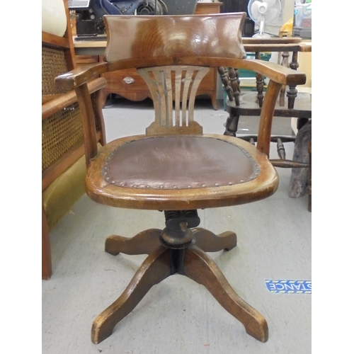 206 - An early 20thC oak framed revolving desk chair, raised on a splayed pedestal base