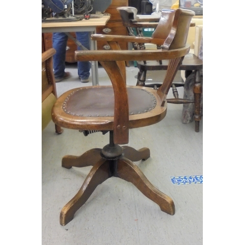 206 - An early 20thC oak framed revolving desk chair, raised on a splayed pedestal base