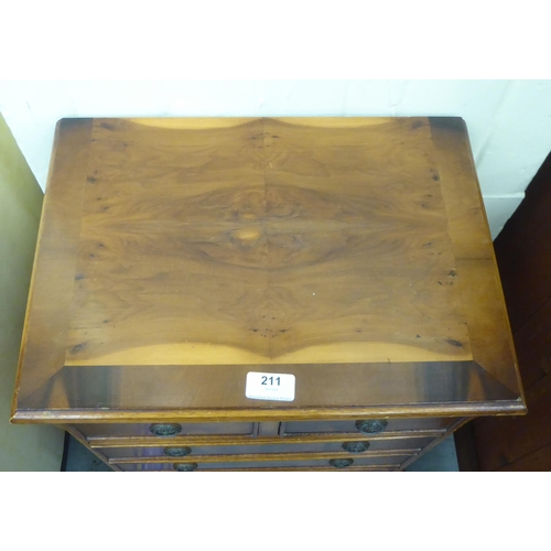 211 - A modern yew finished bedside chest with an arrangement of four short/four long drawers, raised on b... 