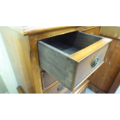 211 - A modern yew finished bedside chest with an arrangement of four short/four long drawers, raised on b... 